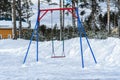 cold, without children cold Playground with lonely standing swings on a chain. the snow and emptiness