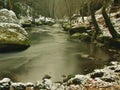 Cold clear water of mountain river in winter time, icicles on boulder Royalty Free Stock Photo