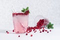 Cold cocktail with lingonberry, ice cubes, straws, ingredients in transparent glass on soft light white wood table with copy space