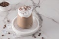 Cold coffee with chocolate milk and ice, with whipped cream and cinnamon in a glass glass on a marble table. cold summer dessert Royalty Free Stock Photo