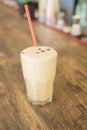 A cold coffee cocktail in a clear glass with a straw on a wooden bar counter Royalty Free Stock Photo