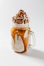 Cold coffee with caramel, chocolate and nuts in glass mug on white background Royalty Free Stock Photo