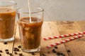 Cold coffee pouring in cream, milk in transparent glasses with ice and straws, on a wooden background, a cooling drink, refreshing Royalty Free Stock Photo