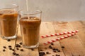 Cold coffee pouring in cream, milk in transparent glasses with ice and straws, on a wooden background, a cooling drink, refreshing Royalty Free Stock Photo