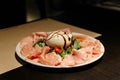 Cold Cuts Burratina: Burrata Cheese served with Parma Ham, Mortadella and Salad. Served in white plate on paper mat Royalty Free Stock Photo