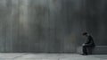 Young depressed businessman sitting on a bench in front of a concrete wall Royalty Free Stock Photo