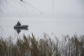 On a cold day in winter, a fisherman on an inflatable boat catches fish Royalty Free Stock Photo