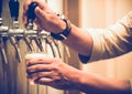 Cold draft beer poured into glass from silver beer dispenser, selective focus