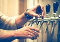 Cold draft beer poured into glass from silver beer dispenser, selective focus