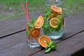 Cold drinks cocktail with red orange and mint in glass and jar. Refreshment lemonade on wooden table. Close up, copy space