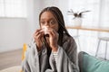 Sick african american woman sneezing, home interior Royalty Free Stock Photo