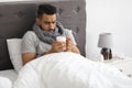 Cold And Flu. Portrait Of Sick Arab Man Drinking Tea In Bed Royalty Free Stock Photo