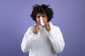 Cold and flu. Sick black teenager sneezing in paper tissue, suffering from rhinitis or sinusitis on violet background Royalty Free Stock Photo