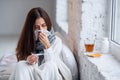 Sick woman caught cold, feeling illness and sneezing in paper wipe. Closeup of beautiful unhealthy girl covered in