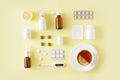 Cold and flu treatment set. Pills, throat spray, medical mask, thermometer, recipe on simple yellow background. Health care