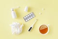 Cold and flu treatment set. Pills, throat spray, thermometer, cup of tea with lemon on simple yellow background. Health care thera