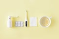 Cold and flu treatment set. Pills, throat spray, thermometer, cup of tea with lemon on simple yellow background. Health care thera