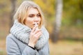 Cold and flu. Young sick woman uses a nose spray at street outside Royalty Free Stock Photo