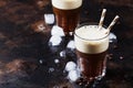 Cold frappe coffee with ice and foam in large glasses on brown b