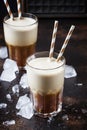 Cold frappe coffee with ice and foam in large glasses on brown b
