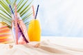 Cold fresh fruit pink and orange drinks with straw in wet glass bottles on tropical beach with blue sea view, sun hat under green. Royalty Free Stock Photo