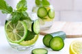 Cold fresh summer drink in glass on bright grey brick wall background. Tasty lemonade with lemon, lime, cucumber, mint and ice. Royalty Free Stock Photo