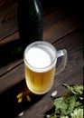 Cold frothy beer in a glass bottle and hops on a dark wooden background Royalty Free Stock Photo