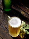 Cold frothy beer in a glass bottle and hops on a dark wooden background Royalty Free Stock Photo