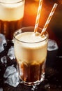 Cold frothy frappe coffee in large glasses on brown background, selective focus