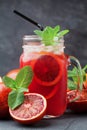 Cold fruit lemonade drink or juice decorated mint leaves in mason glass jar on black background. Royalty Free Stock Photo