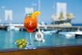 Cold glass of aperol spritz near the sea and boats