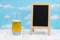 Cold glass of beer with chalkboard on weathered wood with clear sky