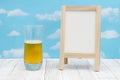 Cold glass of beer with whiteboard on weathered wood with clear sky