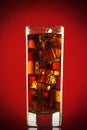 Cold glass of cola drink with ice cubes isolated on red background Royalty Free Stock Photo