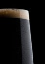 Cold glass of dark beer with foam and dew Royalty Free Stock Photo