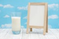 Cold glass of milk with chalkboard on weathered wood with clear sky