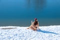 Cold hardy woman practicing half spinal twist yoga pose on snow