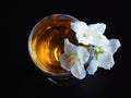 Cold herbal tea in a wine glass with Jasmine flowers on a black background closeup, top view. Flower pattern Royalty Free Stock Photo