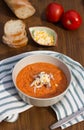 Cold Italian salmorejo soup with grated egg in a bowl on a striped napkin on a wooden table