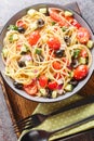 Cold Italian spaghetti salad features fresh veggies and lots of yummy dressing closeup on the bowl. Vertical top view