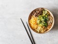 Cold Korean kuksi soup with vegetables, scrambled eggs, beef and noodles in a bowl and chopsticks on a gray background. Top view Royalty Free Stock Photo