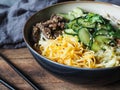 Cold Korean kuksi soup with vegetables, scrambled eggs, beef and noodles in a bowl and chopsticks on rustic wood background Royalty Free Stock Photo