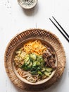 Cold Korean kuksi soup with vegetables, scrambled eggs, beef and noodles in a bowl and chopsticks on a white wood background. Top Royalty Free Stock Photo