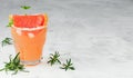 Cold lemonade of fresh grapefruit juice with alcohol or wihtout alcohole and ice cubes decorated a slice of grapefruit, twig mint