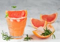 Cold lemonade of fresh grapefruit juice wihtout alcohole and ice cubes decorated a slice of grapefruit, twig mint and rosemary on