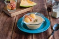 Cold melon soup with thin ham and fresh melon balls in a transparent glass bowl on a brown wooden background. Spanish cuisine