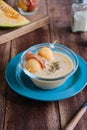 Cold melon soup with thin ham and fresh melon balls in a transparent glass bowl on a brown wooden background. Spanish cuisine