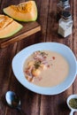 Cold melon soup with thin ham and fresh melon balls in a white ceramic plate on a brown wooden background. Spanish cuisine