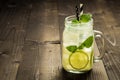Cold Mojito Cocktail with Ice, Lemon and Mint Leaves in Mason Jar on Rustic Dark Wooden Background as Summer Concept Royalty Free Stock Photo