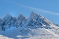 A cold mountain peak covered in snow during winter with a blue sky background. Beautiful landscape of a snowy summit Royalty Free Stock Photo